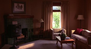 Movie still from “Grosse Pointe Blank” (1997), directed by George Armitage – A living room filled with furniture next to a fire place; Wide shot, High angle
