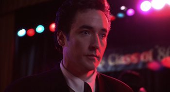 Movie still from “Grosse Pointe Blank” (1997), directed by George Armitage – A person wearing a suit and tie; Close Up shot, Low angle