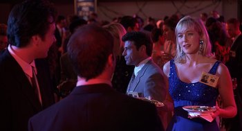 Movie still from “Grosse Pointe Blank” (1997), directed by George Armitage – A group of people standing in a room at a party; Medium shot, Over the shoulder angle