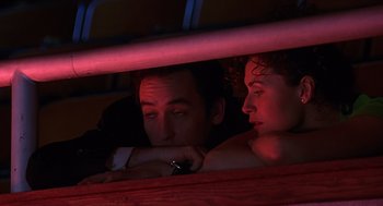 Movie still from “Grosse Pointe Blank” (1997), directed by George Armitage – A man and a woman sitting next to each other; Medium shot, Low angle
