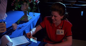 Movie still from “Grosse Pointe Blank” (1997), directed by George Armitage – A woman sitting at a table with a blue table cloth; Medium shot, Over the shoulder angle