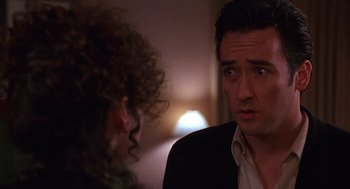Movie still from “Grosse Pointe Blank” (1997), directed by George Armitage – A man and a woman are looking at each other in a room; Close Up shot, Over the shoulder angle