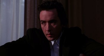 Movie still from “Grosse Pointe Blank” (1997), directed by George Armitage – A person wearing a suit and tie; Close Up shot, Low angle