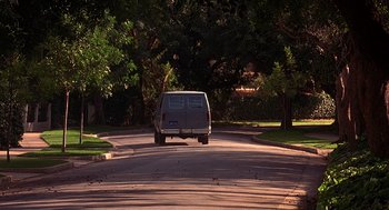 Movie still from “Grosse Pointe Blank” (1997), directed by George Armitage – A van driving down a street near some trees; Wide shot, High angle