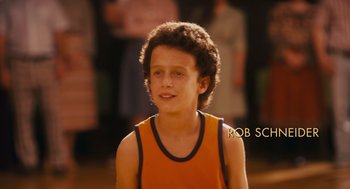 Movie still from “Grown Ups” (2010), directed by Dennis Dugan – A young man in an orange shirt is looking at the camera; Close Up shot, High angle
