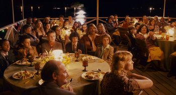 Movie still from “Grown Ups” (2010), directed by Dennis Dugan – A group of people sitting around a table at a party; Wide shot, High angle