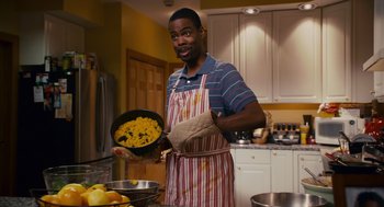 Movie still from “Grown Ups” (2010), directed by Dennis Dugan – A man holding a pan of food in a kitchen; Medium shot, High angle