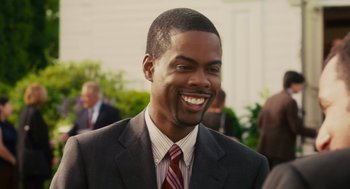 Movie still from “Grown Ups” (2010), directed by Dennis Dugan – A man in a suit and tie smiling; Close Up shot, Over the shoulder angle