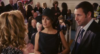 Movie still from “Grown Ups” (2010), directed by Dennis Dugan – A woman wearing a black dress and a black hat in front of a group of people; Medium shot, Over the shoulder angle