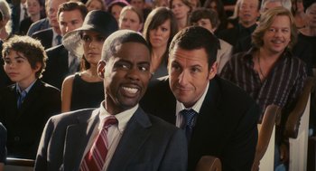 Movie still from “Grown Ups” (2010), directed by Dennis Dugan – A couple of men sitting next to each other in front of a crowd; Medium shot, Over the shoulder angle