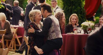 Movie still from “Grown Ups” (2010), directed by Dennis Dugan – A man and a woman are hugging at an event; Medium shot, Over the shoulder angle