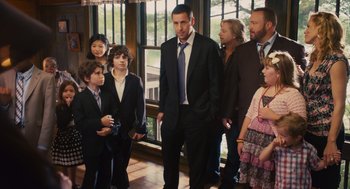 Movie still from “Grown Ups” (2010), directed by Dennis Dugan – A group of people standing in a room with a man in a suit; Medium shot, Over the shoulder angle