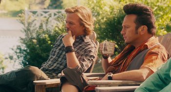 Movie still from “Grown Ups” (2010), directed by Dennis Dugan – Two men are sitting at a table and one is holding a cup; Medium shot, Over the shoulder angle