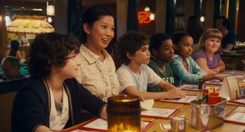 Movie still from “Grown Ups” (2010), directed by Dennis Dugan – A group of people sitting at a table with food; Medium shot, Over the shoulder angle
