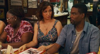 Movie still from “Grown Ups” (2010), directed by Dennis Dugan – A woman sitting next to a man holding a book; Medium shot, Over the shoulder angle