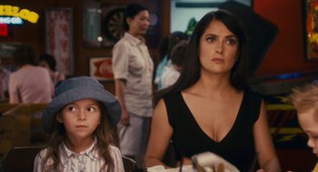 A woman sitting next to a young girl in front of a table