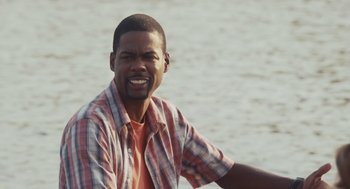 Movie still from “Grown Ups” (2010), directed by Dennis Dugan – A person sitting on a chair near a body of water; Close Up shot, Over the shoulder angle