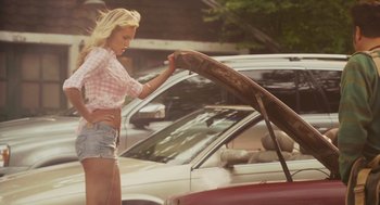 Movie still from “Grown Ups” (2010), directed by Dennis Dugan – A beautiful young woman standing next to a car with the hood open; Medium shot, Low angle