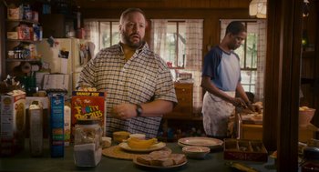 Movie still from “Grown Ups” (2010), directed by Dennis Dugan – A man standing in front of a table with food on it; Medium shot, Over the shoulder angle