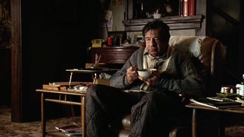 Movie still from “Grumpy Old Men” (1993), directed by Donald Petrie – A man sitting in a chair holding a bowl of food; Medium shot, High angle