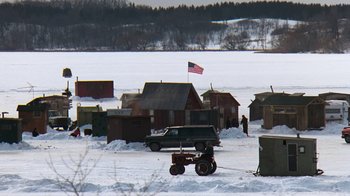 Movie still from “Grumpy Old Men” (1993), directed by Donald Petrie – An american flag flies in the background of a snow - covered lake; Extreme Wide shot, High angle