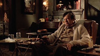 Movie still from “Grumpy Old Men” (1993), directed by Donald Petrie – An older man sitting in a chair in a living room; Medium shot, High angle