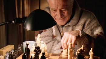 Movie still from “Grumpy Old Men” (1993), directed by Donald Petrie – An older man playing chess with a lamp on his head; Close Up shot, High angle