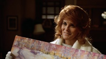 Movie still from “Grumpy Old Men” (1993), directed by Donald Petrie – A woman holding up a painting in front of her face; Close Up shot, Over the shoulder angle