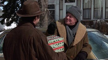 Movie still from “Grumpy Old Men” (1993), directed by Donald Petrie – A man handing a gift to another man outside; Medium shot, Over the shoulder angle