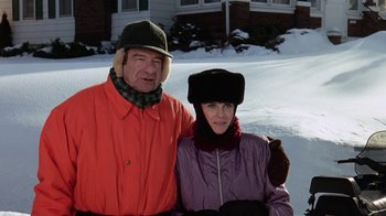 Movie still from “Grumpy Old Men” (1993), directed by Donald Petrie – An older man and woman pose for a picture in the snow; Medium shot, High angle