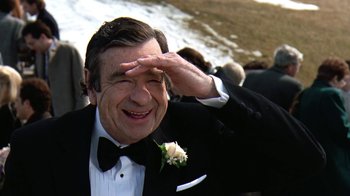 Movie still from “Grumpy Old Men” (1993), directed by Donald Petrie – A man in a tuxedo saluting in front of a group of people; Close Up shot, Over the shoulder angle
