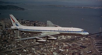 Movie still from “Guess Who's Coming to Dinner” (1967), directed by Stanley Kramer – An airplane is flying over a city with buildings in the background; Extreme Wide shot, Overhead angle