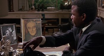 Movie still from “Guess Who's Coming to Dinner” (1967), directed by Stanley Kramer – A man sitting at a table in front of a painting of an older man; Close Up shot, Over the shoulder angle