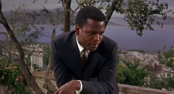 Movie still from “Guess Who's Coming to Dinner” (1967), directed by Stanley Kramer – A man wearing a suit and tie leaning against a wall; Medium shot, Low angle