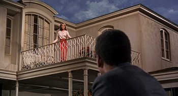 Movie still from “Guess Who's Coming to Dinner” (1967), directed by Stanley Kramer – A woman standing on top of an iron railing on top of a balcony; Wide shot, Low angle
