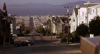 Movie still from “Guess Who's Coming to Dinner” (1967), directed by Stanley Kramer – A view of a city from a hill with cars parked on the side; Extreme Wide shot, High angle