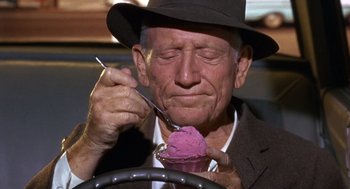 Movie still from “Guess Who's Coming to Dinner” (1967), directed by Stanley Kramer – An old man eating a purple ice - cream while sitting in a car; Close Up shot, Over the shoulder angle