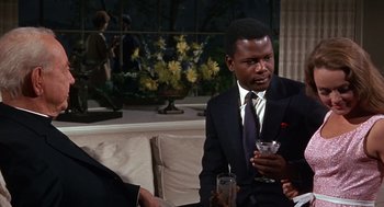 Movie still from “Guess Who's Coming to Dinner” (1967), directed by Stanley Kramer – A man sitting on a couch holding a wine glass; Medium shot, Over the shoulder angle