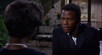 Movie still from “Guess Who's Coming to Dinner” (1967), directed by Stanley Kramer – A man in a business suit talking to a woman in a suit; Close Up shot, Over the shoulder angle