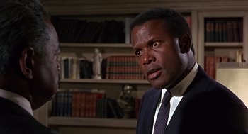 Movie still from “Guess Who's Coming to Dinner” (1967), directed by Stanley Kramer – A man wearing a suit and tie in a room; Close Up shot, Over the shoulder angle