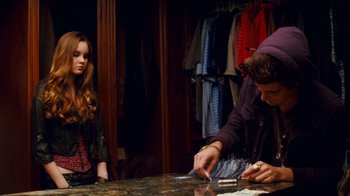 Movie still from “Trespass” (2011), directed by Joel Schumacher – A man and a woman cutting paper at a counter; Medium shot, Over the shoulder angle