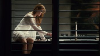 Movie still from “Trespass” (2011), directed by Joel Schumacher – A woman in a white dress sitting at a table; Medium shot, Low angle