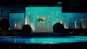 Movie still from “Trespass” (2011), directed by Joel Schumacher – A pool with a lit up building in the background at night; Extreme Wide shot, Low angle
