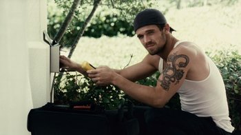 Movie still from “Trespass” (2011), directed by Joel Schumacher – A man with a tattoo on his arm holding an apple; Medium shot, High angle
