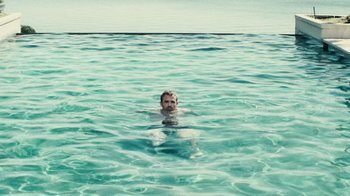 Movie still from “Trespass” (2011), directed by Joel Schumacher – A man in the water in front of a body of water; Wide shot, High angle