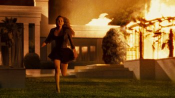 Movie still from “Trespass” (2011), directed by Joel Schumacher – A woman running in front of a building on a lawn; Wide shot, Over the shoulder angle