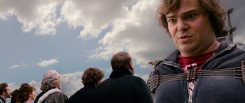 Movie still from “Gulliver's Travels” (2010), directed by Rob Letterman – A group of people that are standing in the grass; Close Up shot, Over the shoulder angle