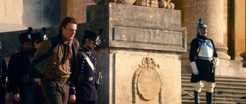 Movie still from “Gulliver's Travels” (2010), directed by Rob Letterman – Two men in uniforms are standing in front of a stone wall; Wide shot, Low angle