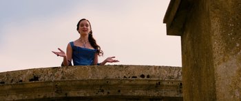 Movie still from “Gulliver's Travels” (2010), directed by Rob Letterman – A woman in a blue dress standing next to a stone wall; Medium shot, Low angle