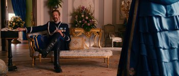 Movie still from “Gulliver's Travels” (2010), directed by Rob Letterman – A man sitting on top of a couch next to a table; Wide shot, Over the shoulder angle